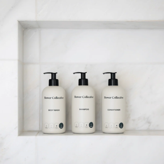 Bower Collective dispenser collection on a white shelf in a bathroom (body wash, shampoo and conditioner)