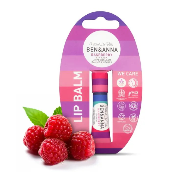 Ben & Anna lip balm in purple shades paper tube packaging in Raspberry, shown alongside some fresh raspberries
