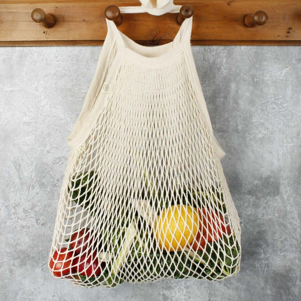Natural coloured strong bag made with recycled cotton, with long handles, shown hanging on a hook with fruit and veg inside