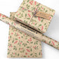 PlanetWrapIt recycled kraft wrapping paper in Christmas mistletoe (brown paper with printed red berries and green leaves) with PlanetWrapIt paper label alongside a wrapped parcel