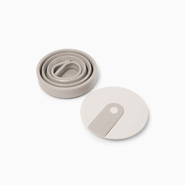 Collapsible cup 16oz shown collapsed in warm grey with flexible straw inside