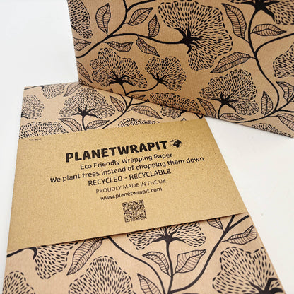 Planet Wrapit eco-friendly kraft wrapping paper with black floral design and PlanetWrapIt paper label shown alongside a wrapped parcel.