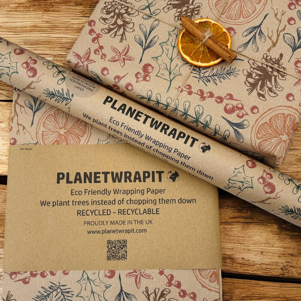 PlanetWrapI recycled kraft wrapping paper in Christmas dried orange (brown background with images of dried oranges, pine cones, foliage) shown alongside a wrapped parcel with dried orange and cinnamon.