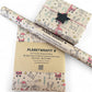 PlanetWrapIt recycled kraft wrapping paper in Christmas Santa and Rudolph (brown paper with printed Santas, Rudolphs and North Pole signs) with PlanetWrapIt paper label alongside wrapped parcel