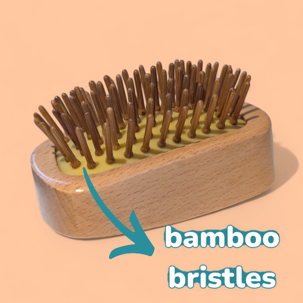 Wooden detangling brush with bamboo bristles on a peach background with text reading 'bamboo bristles'