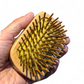 Wooden detangler hairbrush with bamboo bristles held in a hand against a white background