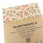 PlanetWrapIt recycled kraft wrapping paper in Christmas mistletoe (brown paper with printed red berries and green leaves) with PlanetWrapIt paper label