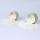 Green cardboard cylinder box lids with white fragrance beads shown inside