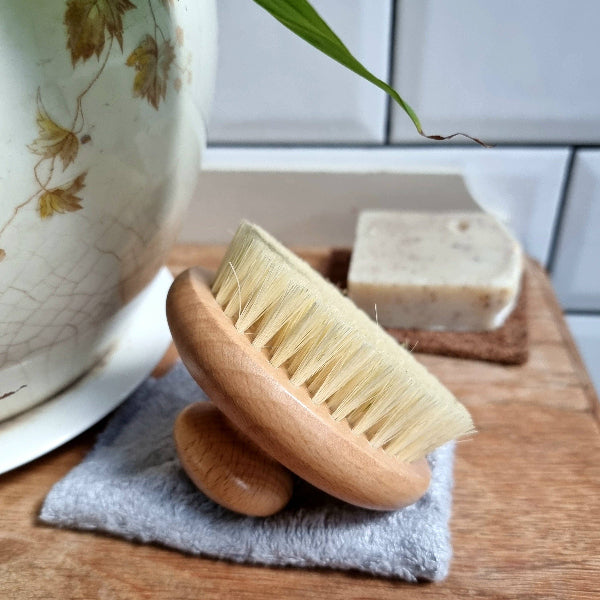 Wooden body brush on a towel with soap in the background