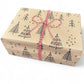 PlanetWrapIt recycled kraft wrapping paper in Christmas trees black (brown paper with printed black Christmas trees) shown on wrapped parcel with red twine