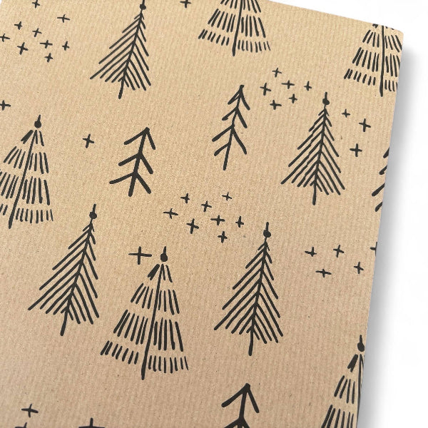 PlanetWrapIt recycled kraft wrapping paper in Christmas trees black (brown paper with printed black Christmas trees) shown close up