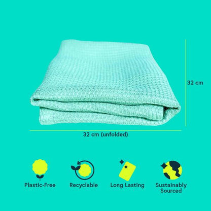 A folded mint green textured all-purpose cloth on a bright teal background, with measurement lines indicating 32 cm by 32 cm (unfolded). Small feature icons below read Plastic-Free, Recyclable, Long Lasting, and Sustainably Sourced.