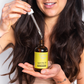 Corinne Taylor natural argan hair oil in glass bottle shown in hand with oil dropper dripping 