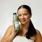 Woman holding glass bottle of UpCircle bath salts near face