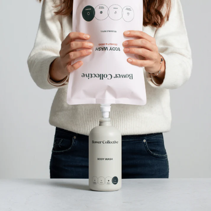 Person holding a body wash refill by Bower Collective, dispensing into their body wash refill pump dispenser. 