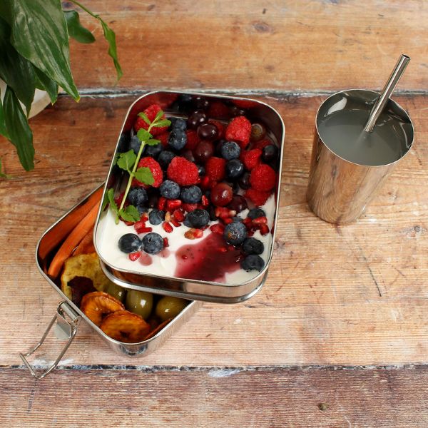 Buruni two-tier leak-resistant stainless steel lunchbox shown with yoghurt and fruit in top layer and a bagel in lower level alongside stainless steel cup and straw