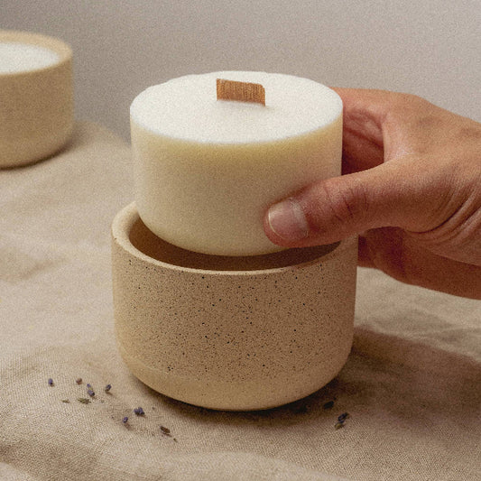 Candle pot with a hand holding a candle above it ready to slot into place