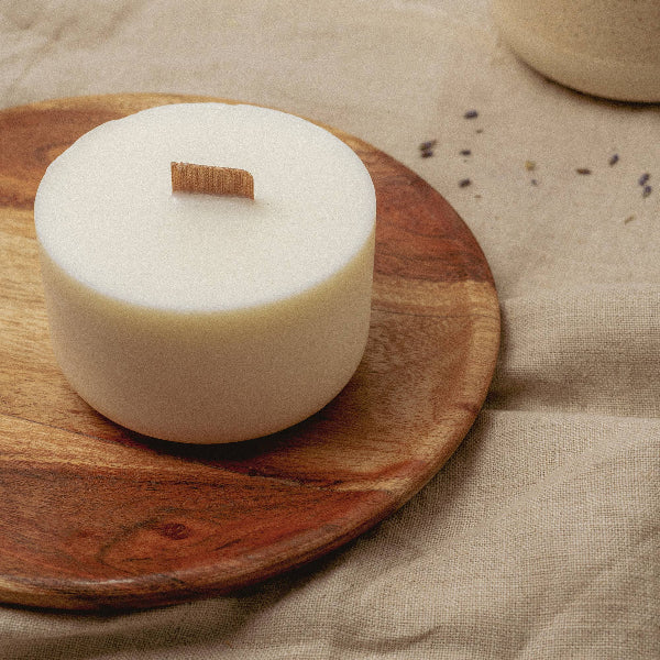 White soy wax candle refill (unwrapped) on a wooden plate with a beige fabric background