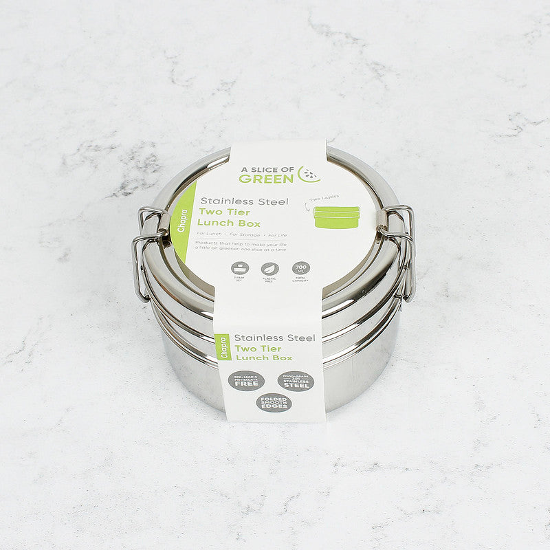 Stainless steel stackable round lunch boxes with paper wrapping on a white surface.