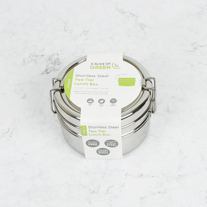 Stainless steel stackable round lunch boxes with paper wrapping on a white surface.