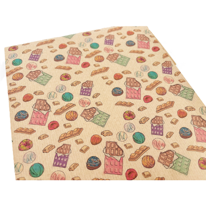Handmade recycled wrapping paper in Chocolates designs (brown kraft paper with and-drawn style colourful chocolate bars and pieces of chocolate) shown close up