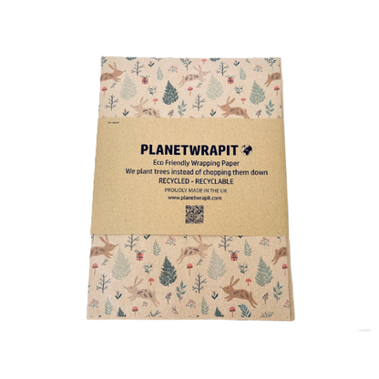 Handmade recycled Christmas paper in Christmas bunnies design, kraft paper background with colourful leaping bunnies and woodland scenes, shown with paper band label 
