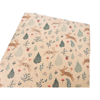 Handmade recycled Christmas paper in Christmas bunnies design, kraft paper background with colourful leaping bunnies and woodland scenes, shown close up