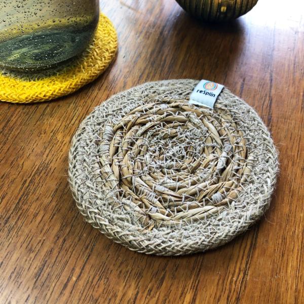 Round seagrass woven coaster with jute trim, on a wooden surface with a ReSpiin brand label.
