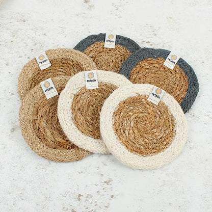 Set of 6 seagrass coasters with jute trim in natural tones on a marble surface