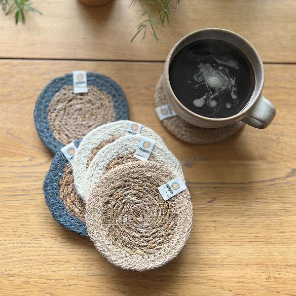 Set of 6 seagrass coasters with jute trim in natural tones alongside a mug with hot drink