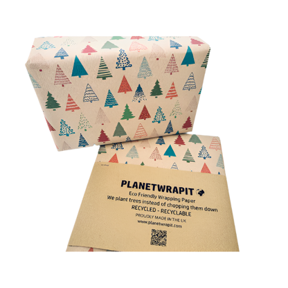 Parcel wrapped in recycled handmade wrapping paper in Colourful Christmas Trees design (brown kraft background with colourful Christmas trees in a hand-drawn style) shown on a wrapped parcel next to the paper with paper wrapper