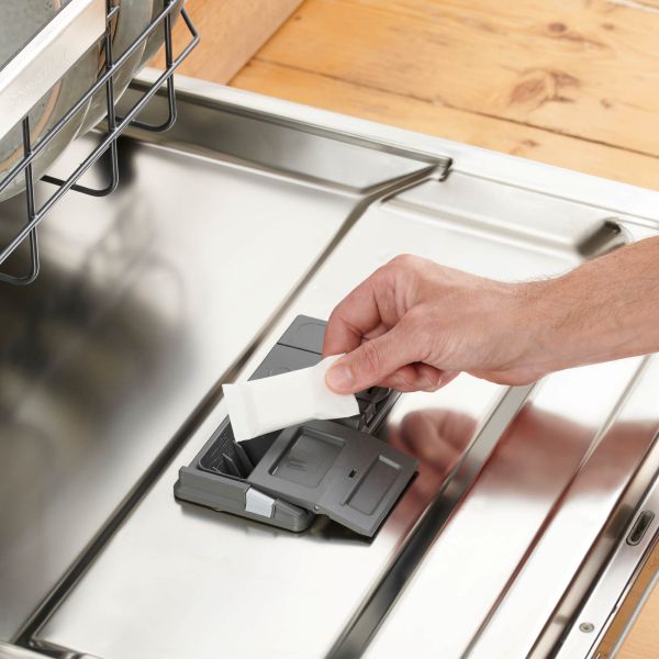 Person putting a dishwasher tab in dishwasher 