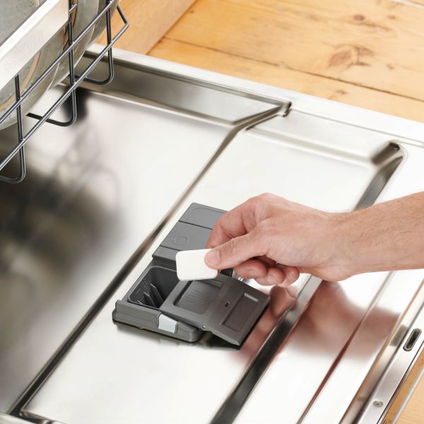 Person putting a dishwasher tab in dishwasher 