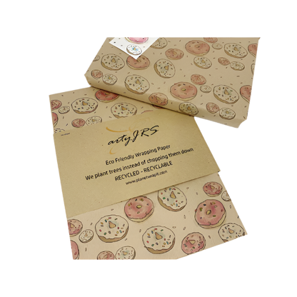 Eco-friendly recyclable wrapping paper in doughnuts design (brown paper with pink and white sprinkled doughnuts) shown alongside a wrapped box