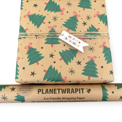 Planetwrapit Christmas wrapping paper roll and wrapped gift box. The wrapping paper has a natural kraft brown background with a pattern of green Christmas trees, pink bows, and black stars.