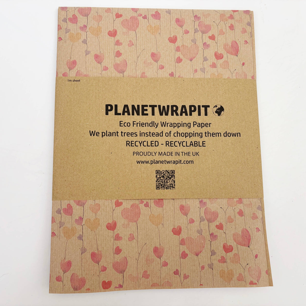 A Planet Wrapit eco-friendly wrapping paper roll with a brown kraft paper centre featuring pink, red, and orange hearts on a brown kraft background, shown on a white surface.