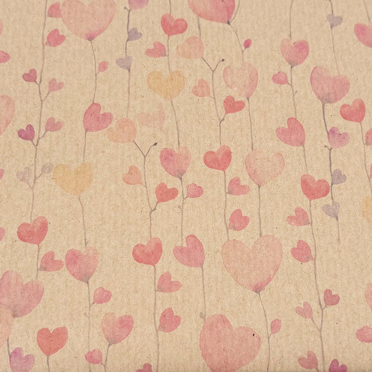 A Planet Wrapit eco-friendly wrapping paper shown close up with a brown kraft paper centre featuring pink, red, and orange hearts on a brown kraft background.