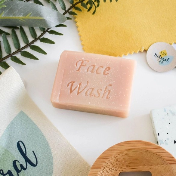 Facial soap bar (grapefruit and lemongrass) shown with greenery and a wooden soapdish, the words 'Facial wash' stamped on the bar