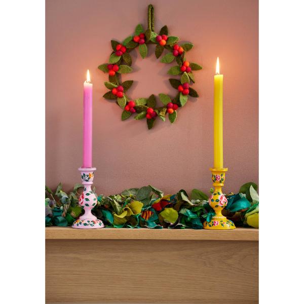 Felt berry wreath with green felt leaves and red felt berries, hanging on a wall with candles and recycled sari tinsel