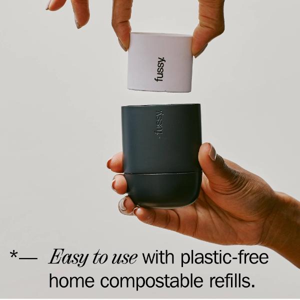Hand putting a 'fussy' deodorant refill into its reusable container with text reading "Easy to use with plastic-free home compostable refills"