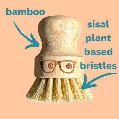 Wooden 'geeky' pot brush with a spectacled face design on a peach background with text "bamboo, sisal plant based bristles"
