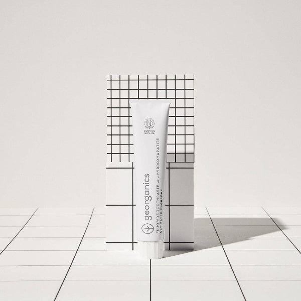 Georganics toothpaste activated charcoal and box on black and white geometric background