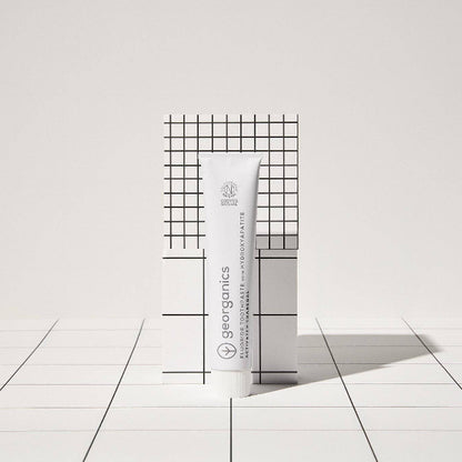 Georganics toothpaste activated charcoal and box on black and white geometric background