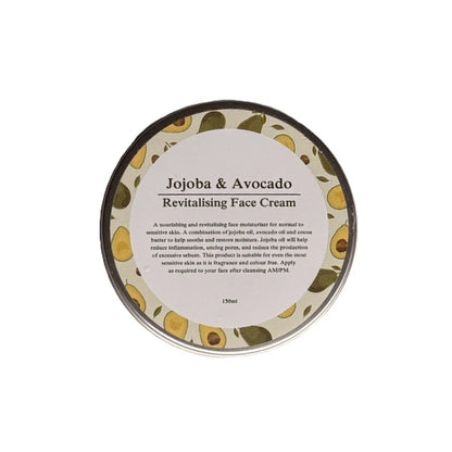 A round metal tin of Jojoba & Avocado Revitalising Face Cream, featuring a cream-colored label with black text and a border of illustrated avocados, set against a plain white background.