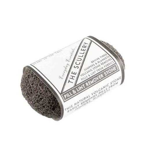 Natural volcanic jumper stone with a paper label saying "Pill and lint remover stone, revive tired jumpers and blankets, volcanic stone removes pill and lint from fabric"
