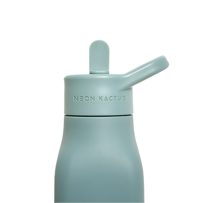 Kids reusable silicone bottle in Happy Camper colourway (an olive green) shown close up with straw lid on