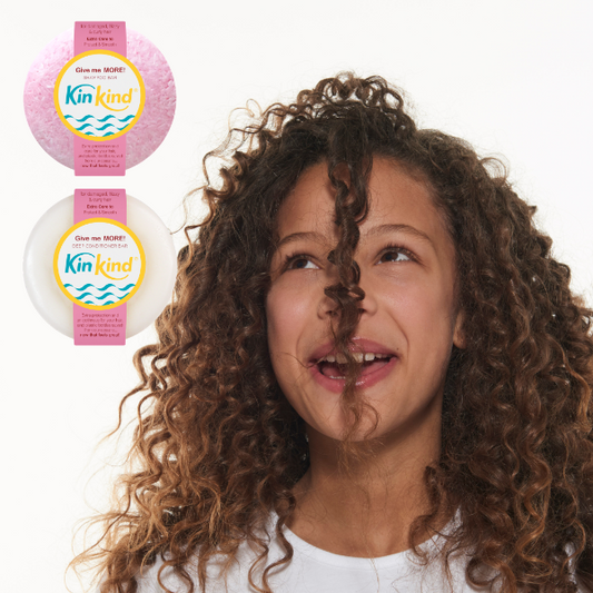 Woman with curly hair looking to the side, with KinKind shampoo and conditioner bars in the corner.
