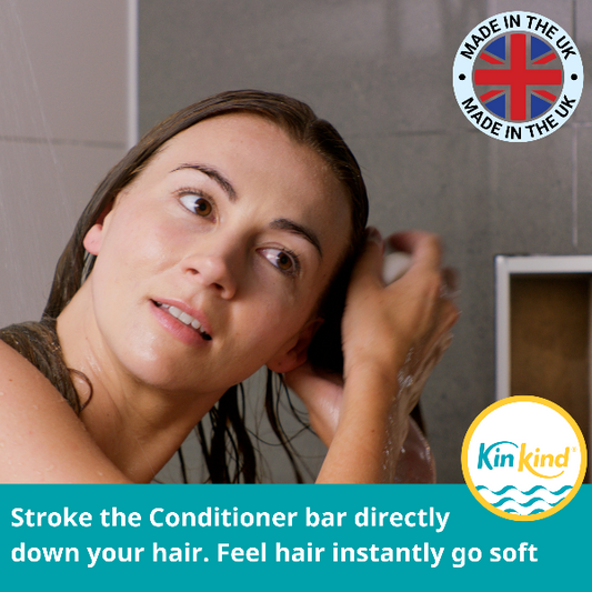Woman applying conditioner to her hair with a 'Made in the UK' and 'Kin+Kind' logo in the corner and the text "Stroke the conditioner bar directly down your hear. Feel hair instantly go soft."