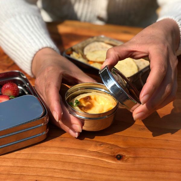 Mini food container in a hand with lid shown off and food inside
