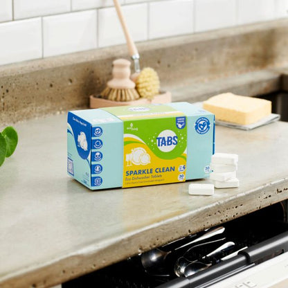 Box of Tabs Sparkle Clean on a kitchen counter with cleaning tools in the background